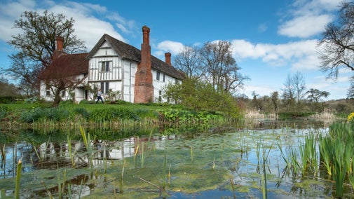 The manor stands surrounded by autumnal colours and the moat.